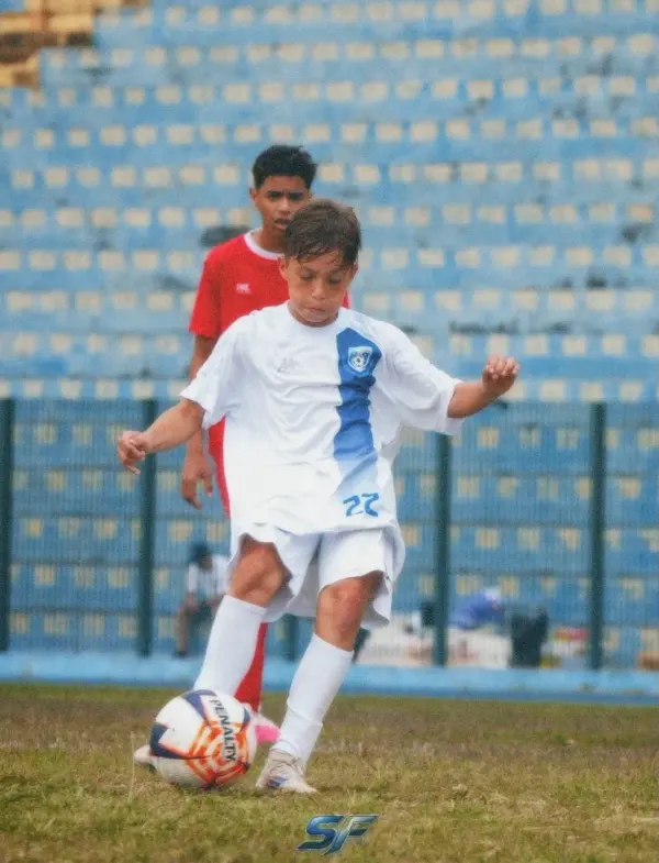 Atleta de branco batendo na bola num estádio.